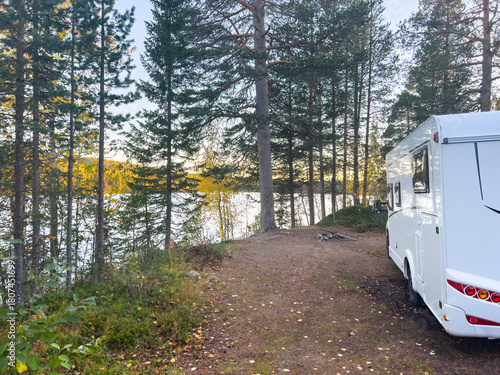 Motorhome driving on a scenic road in Kiruna, Sweden, with autumn foliage and beautiful lake views.