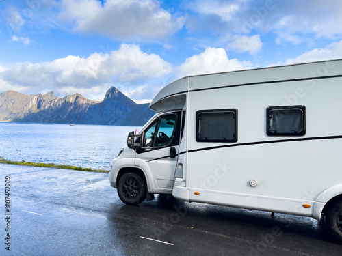 A motorhome parked by the road in the autumn landscape of Senja Island, Northern Norway, with fjords and mountains.