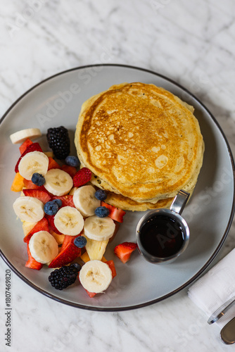 pancakes with fruit and maple syrup in hard light