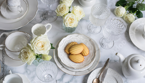 Elegant White Tea Set with Madeleine Cookies and White Roses on Marble Surface