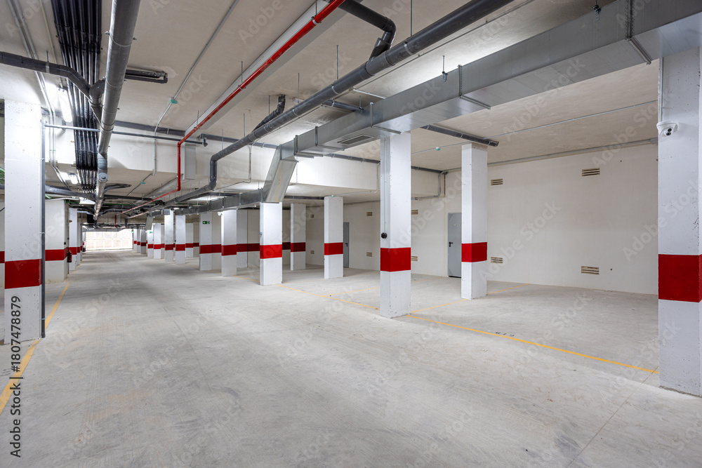 Obraz premium Modern underground parking area with ventilation pipes and marked parking spots