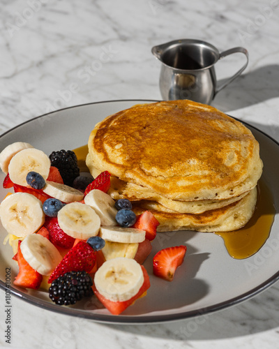 pancakes with fruit and maple syrup in hard light