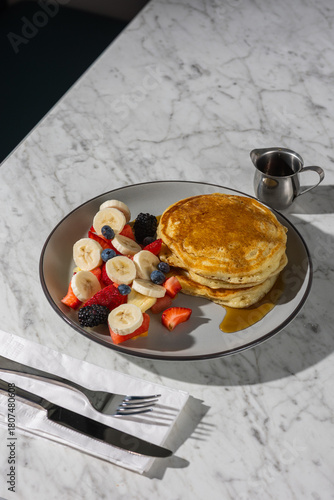 pancakes with fruit and maple syrup in hard light