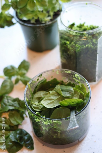 The process of preparing pasta with pesto from spinach, basil, green peas and green parsley: mixing the leaves