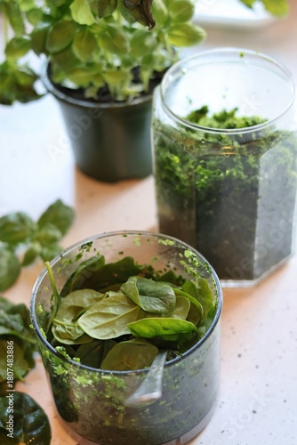 The process of preparing pasta with pesto from spinach, basil, green peas and green parsley: mixing the leaves