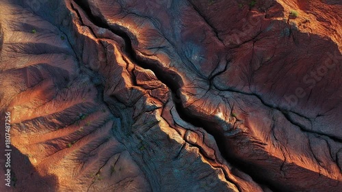 Aerial Top-Down View of Deeply Eroded Arid Landscape with Winding Dry Riverbed and Geological Patterns