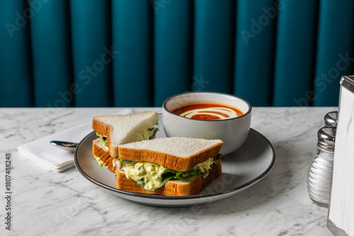 egg salad sandwich with tomato soup on marble table