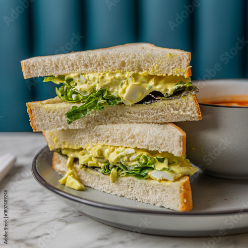 egg salad sandwich with tomato soup on marble table