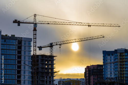 Construction Cranes Silhouetted Against Sunset Sky