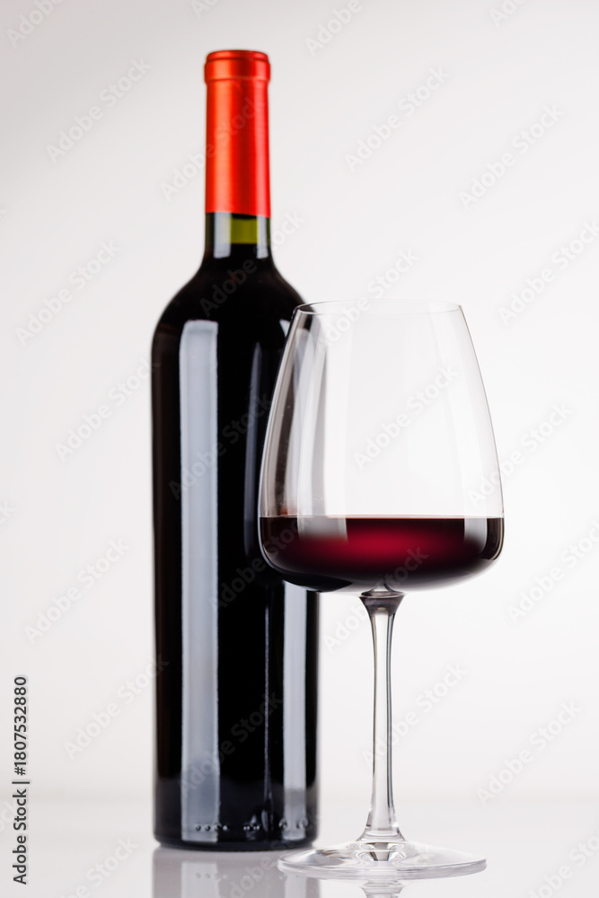 Naklejka premium Red wine bottle and glass on white background