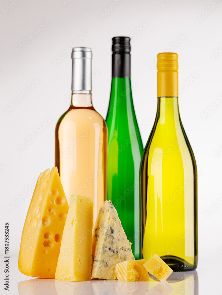 Fototapeta premium Assorted cheeses and wine bottles on white background