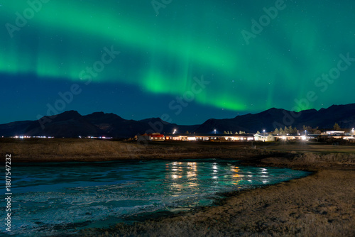 Northern Lights above Höfn with visible green arcs and light cloud cover.
