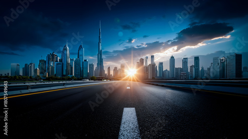 A panoramic view of a city skyline at sunset with a road leading towards the horizon and the sun shining brightly