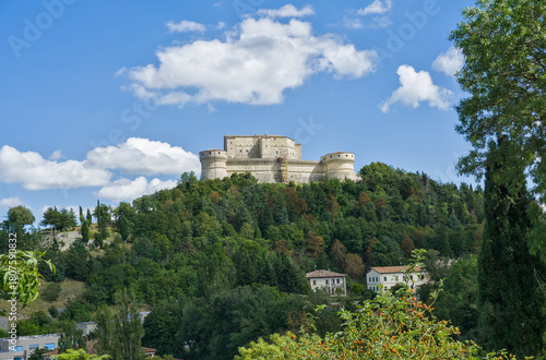 The imposing Forte di San Leo (San Leo Fortress) perched on a steep, forested hill in Italy.