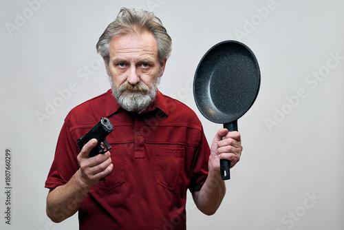 Older man with wrinkles on face skin posing as aggressor in studio