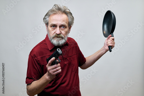 Older man with wrinkles on face skin posing as aggressor in studio