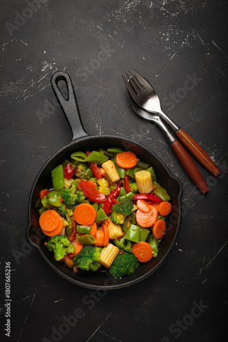 Colorful vegetables broccoli carrot green beans bell pepper stir fried in a cast iron skillet, presenting a healthy and fresh vegetarian meal