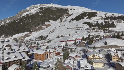 Andermatt, Switzerland in Winter. Aerial of mountain village in Swiss alps in Canton Uri on sunny day after snow fall. 