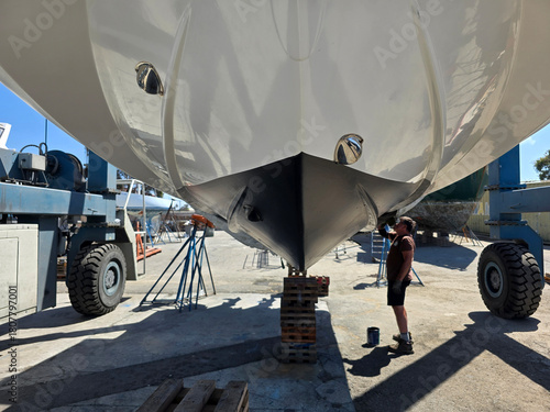Applying new bottom antifouling paint on boat hull.