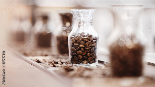 Bilde på lerret Fresh coffee beans after roasting in glass bottle for variety selection, blurred