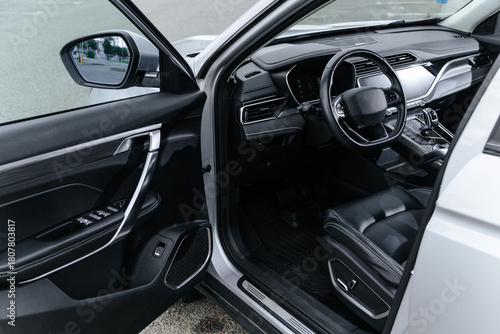 Modern black leather car interior with open driver door, showcasing dashboard