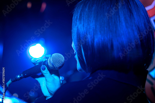 Canvastavla Female singer performing live on stage with blue spotlight