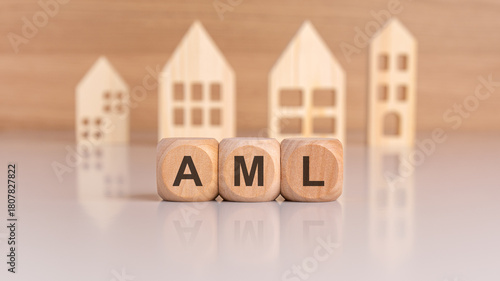 wooden cubes spelling AML in front of model houses, symbolizing anti-money laundering