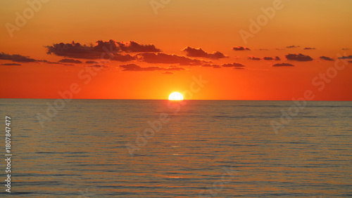 Orange sun rising on the horizon of calm sea