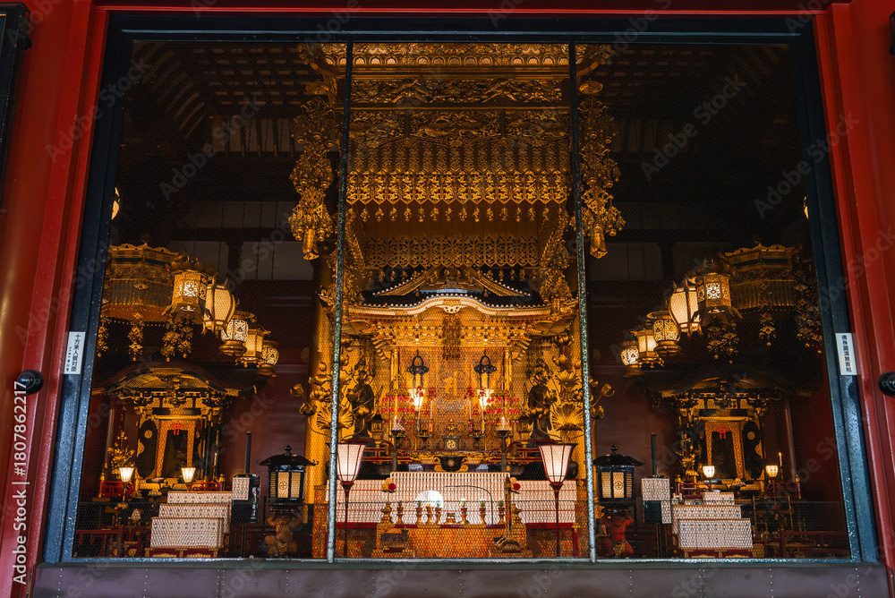 Obraz premium A gold altar glows within a Nara temple, viewed through red pillars. Chandeliers, canopies, and lanterns frame the central shrine in soft daylight, formal and reverent.