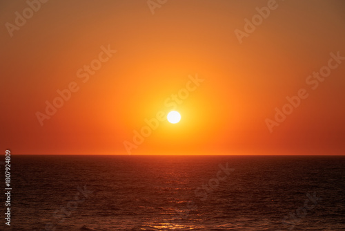 Bright sun setting above the Atlantic Ocean with clear orange sky, Portugal, Ovar – Furadouro, 9 October 2025