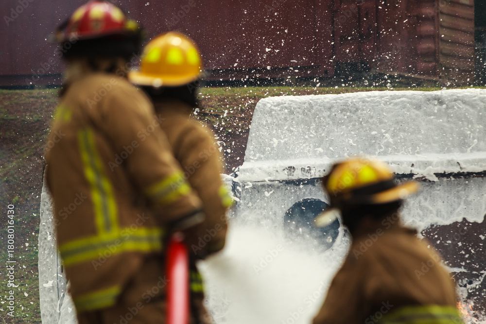 Fototapeta premium Firefighters spraying foam water to control extinguish an intense blaze.