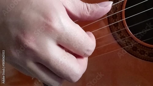 A close up of a right guitarist hand that  touching the acoustic guitar strings and practicing a piece