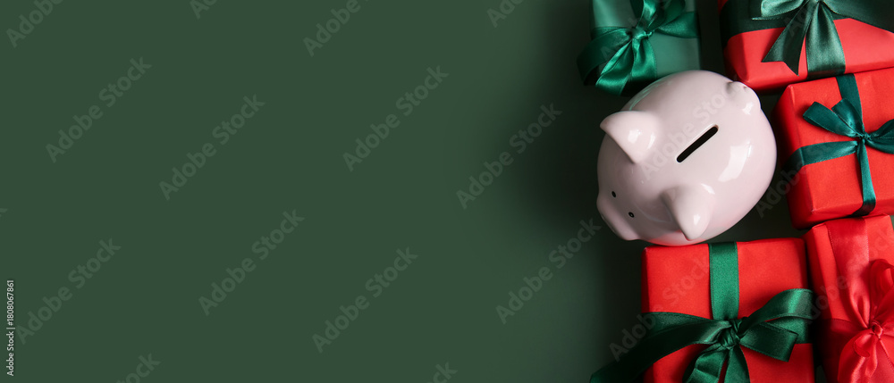 Naklejka premium Piggy bank and different Christmas gifts on green background