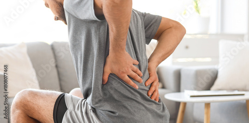 Принти на полотні Sporty young man suffering from back pain on fitball at home