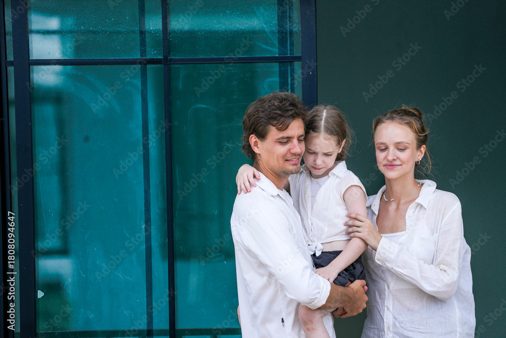 Obraz premium A happy young family at their new home. The father holds his excited daughter and points forward, sharing a moment of joyful discovery and planning for the future with his smiling wife.