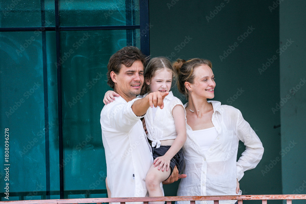 Obraz premium A happy young family at their new home. The father holds his excited daughter and points forward, sharing a moment of joyful discovery and planning for the future with his smiling wife.