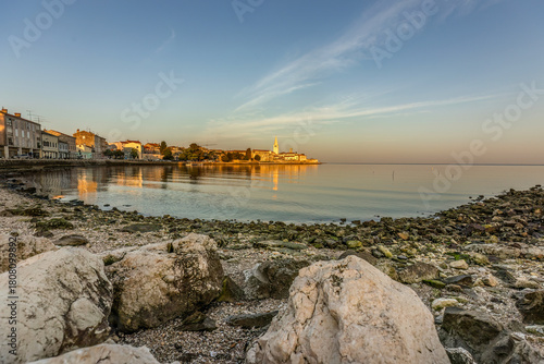 Fototapeta Naklejka Na Ścianę i Meble -  Sunset view of Poreč, Croatia from the rocky shoreline with warm reflections and calm Adriatic evening light