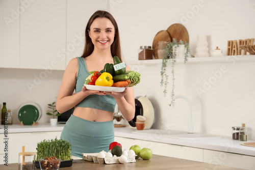 Sporty young woman with fresh vegetables in kitchen. Keto diet concept