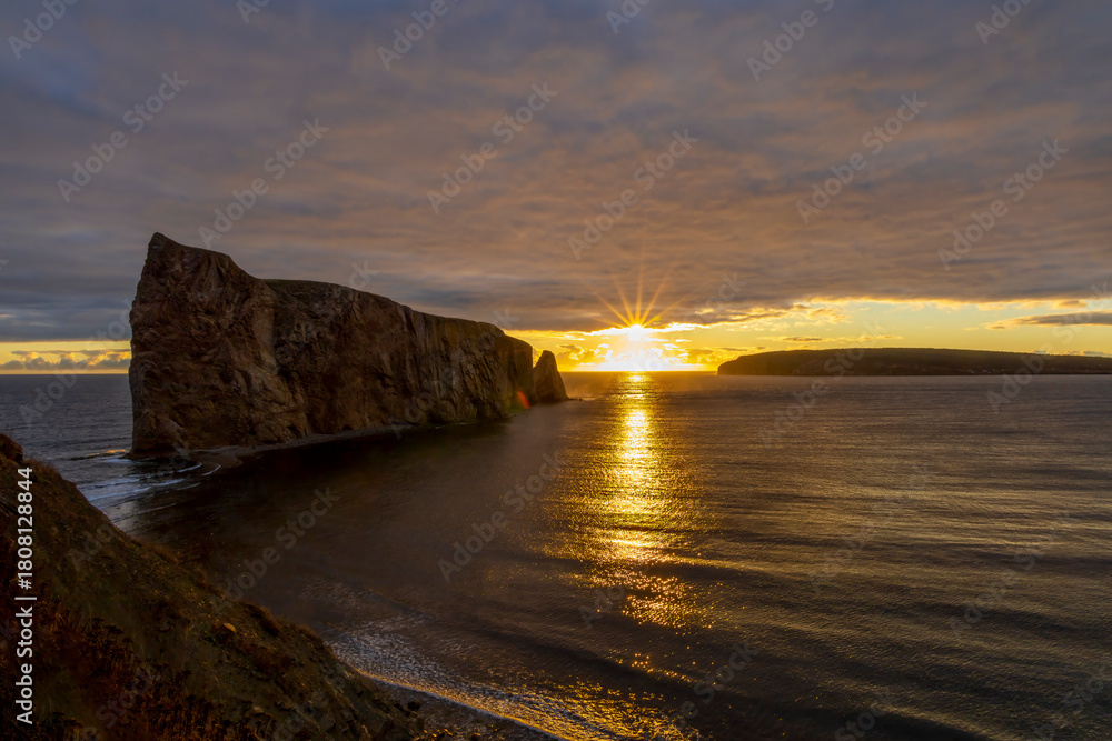 Fototapeta premium Breathtaking sunrise over Perce Rock, Gaspe Peninsula, Quebec. Captured in stunning morning light, this iconic landmark offers a serene and picturesque view.