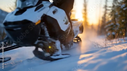 Person riding snowmobile through snowy forest at golden hour