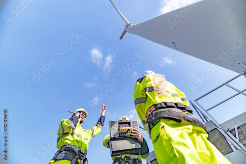 A team of engineers celebrates success after completing wind turbine maintenance at a wind farm. Renewable energy teamwork, green power, and sustainable energy practices in action.