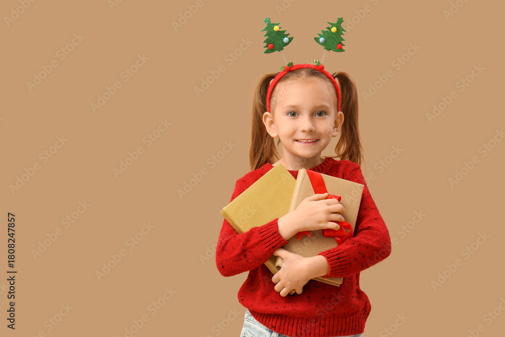 Naklejka premium Cute little girl with books on beige background. Christmas celebration