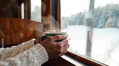 Woman holding warm mug while enjoying winter travel on train  
