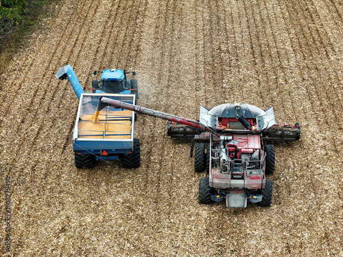 Aerial view of a combine offloading corn into a grain cart being pulled by a tractor