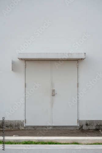 Closed white double metal service doors on a modern industrial or commercial building exterior facade.