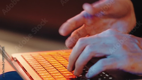  close-up shot of a mans actively typing on expensive laptop and moving hands. background is blurred, night scene