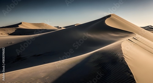 Fototapeta Naklejka Na Ścianę i Meble -  Vast desert landscape with sculpted sand dunes under a clear twilight sky