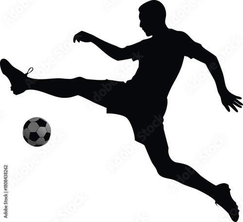 A silhouette of an athlete kicking a soccer ball in mid air