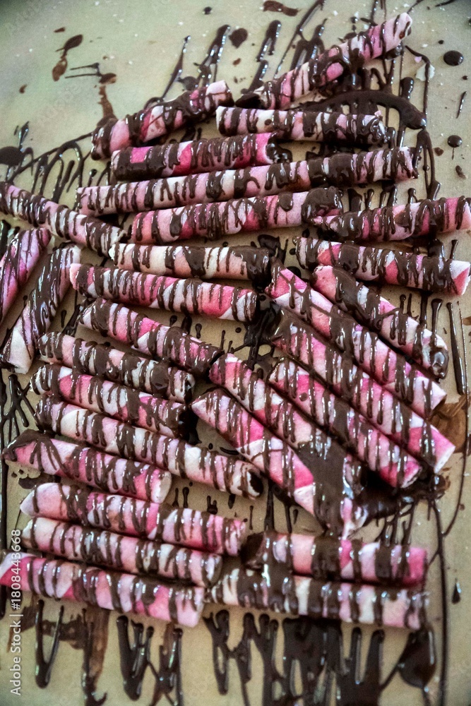Fototapeta premium Chocolate covered pretzels with pink and white icing on a table