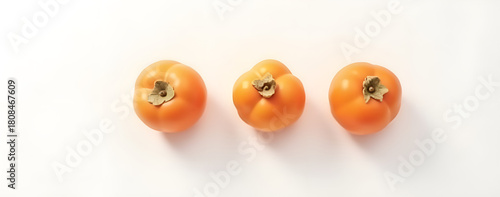 Three ripe persimmons arranged on a white background  